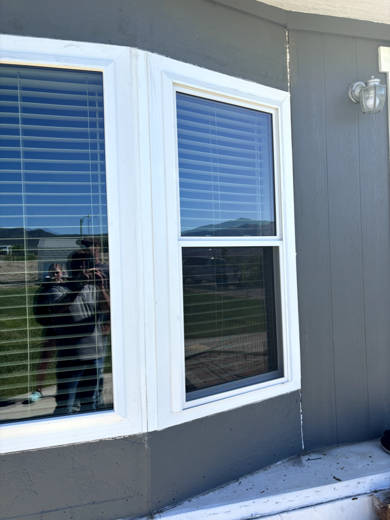 Reflection in window with mountains visible.