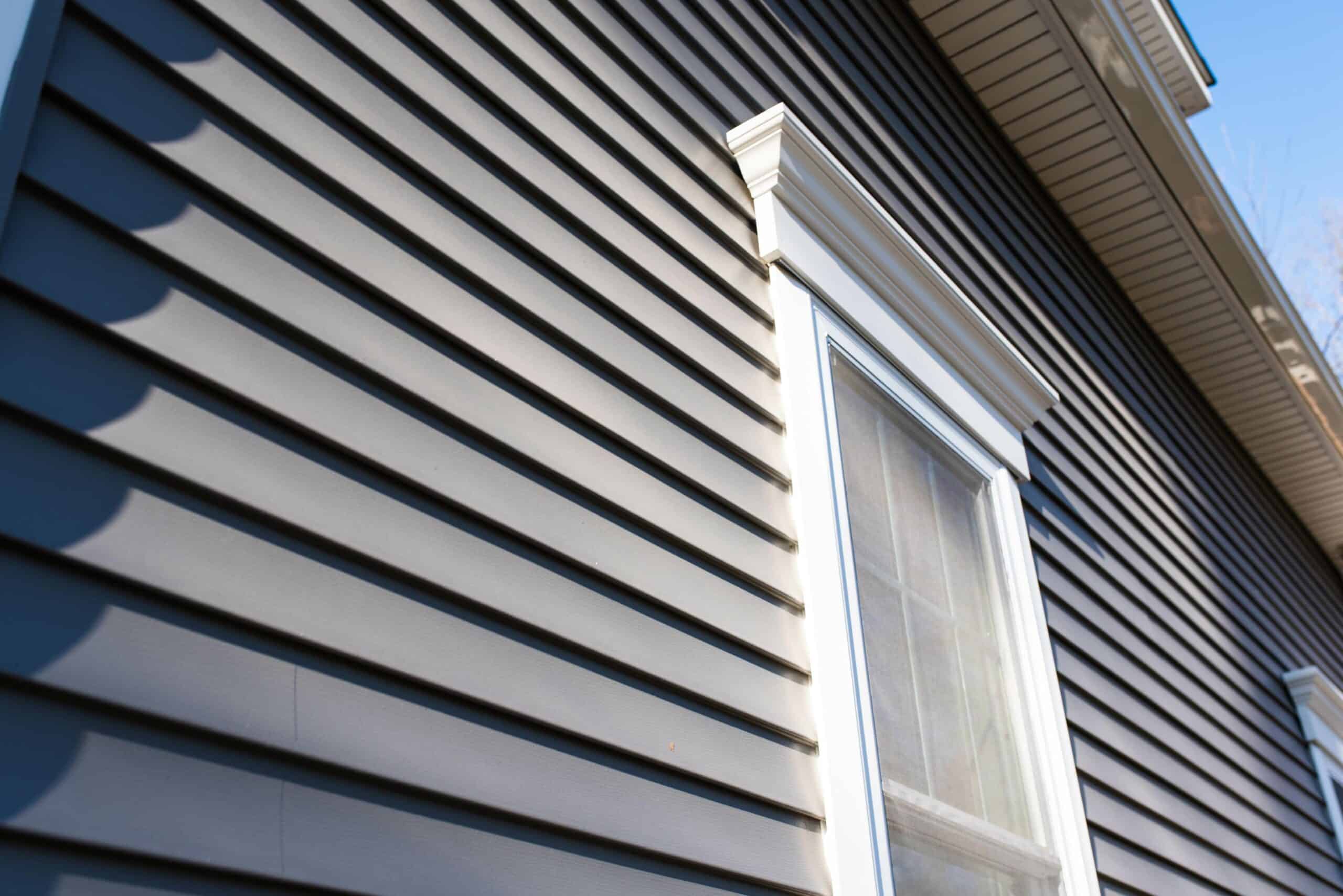 Close-up of modern siding and window installation on a house exterior.
