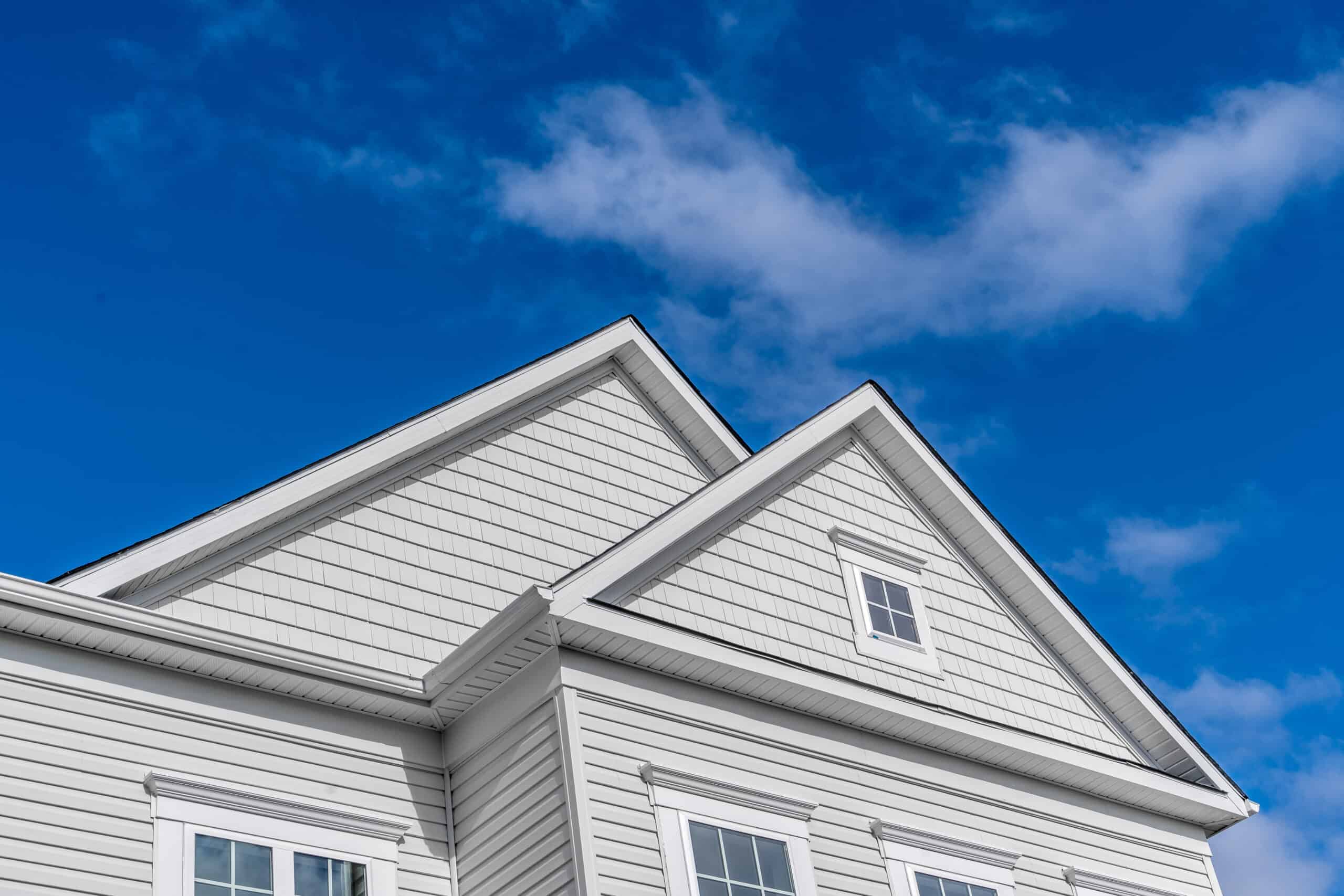 White house with gable roofs and windows, showcasing modern siding and architecture.