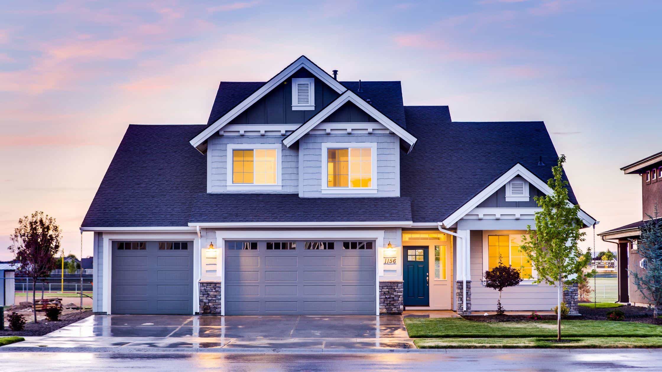 Beautiful modern house with large windows and a spacious garage at sunset.