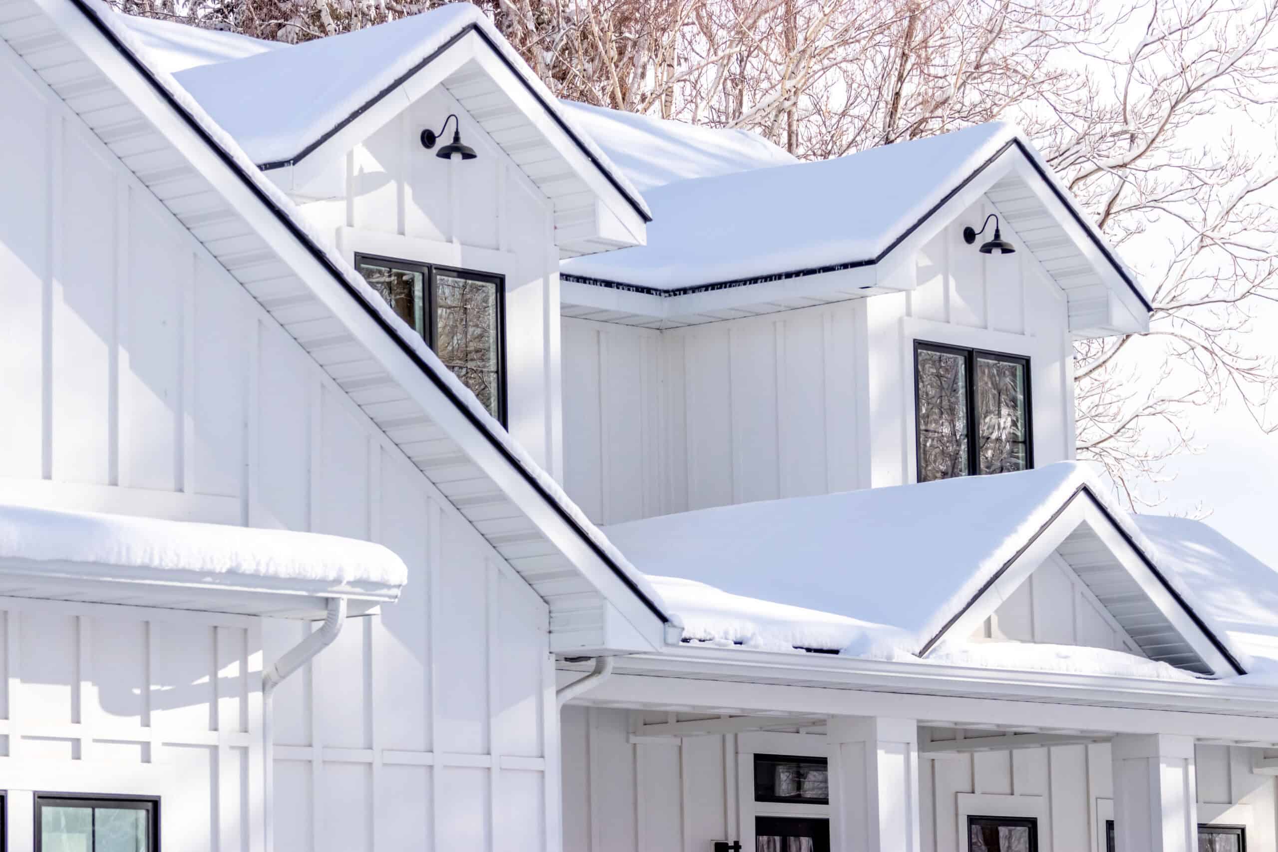 Modern white house with large windows and snow-covered roof, showcasing NTY Windows products.